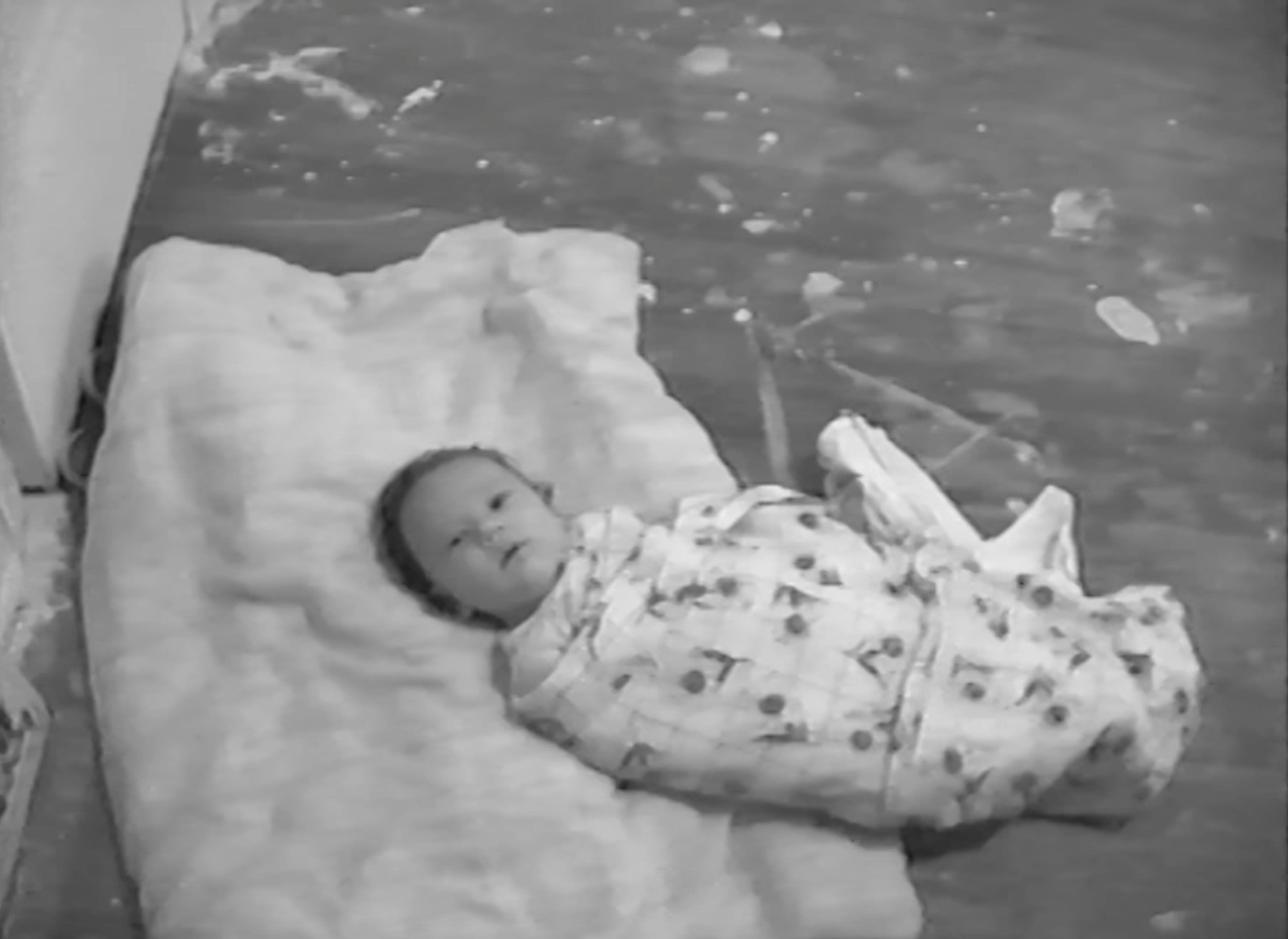 Newborn Akiane swaddled on a sheepskin on a stained floor