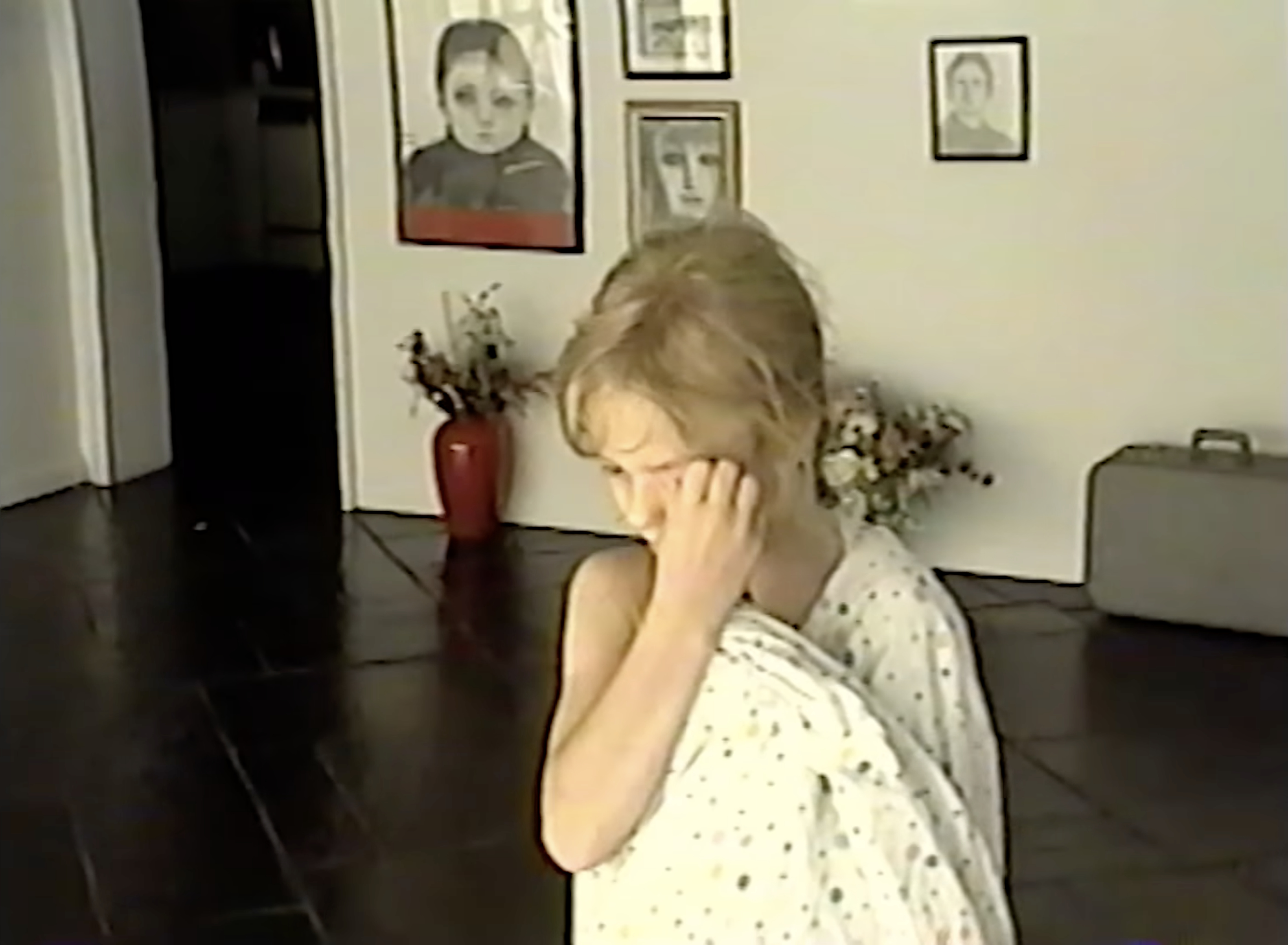 Young Akiane in a polka-dot dress beneath her early portrait drawings on the wall