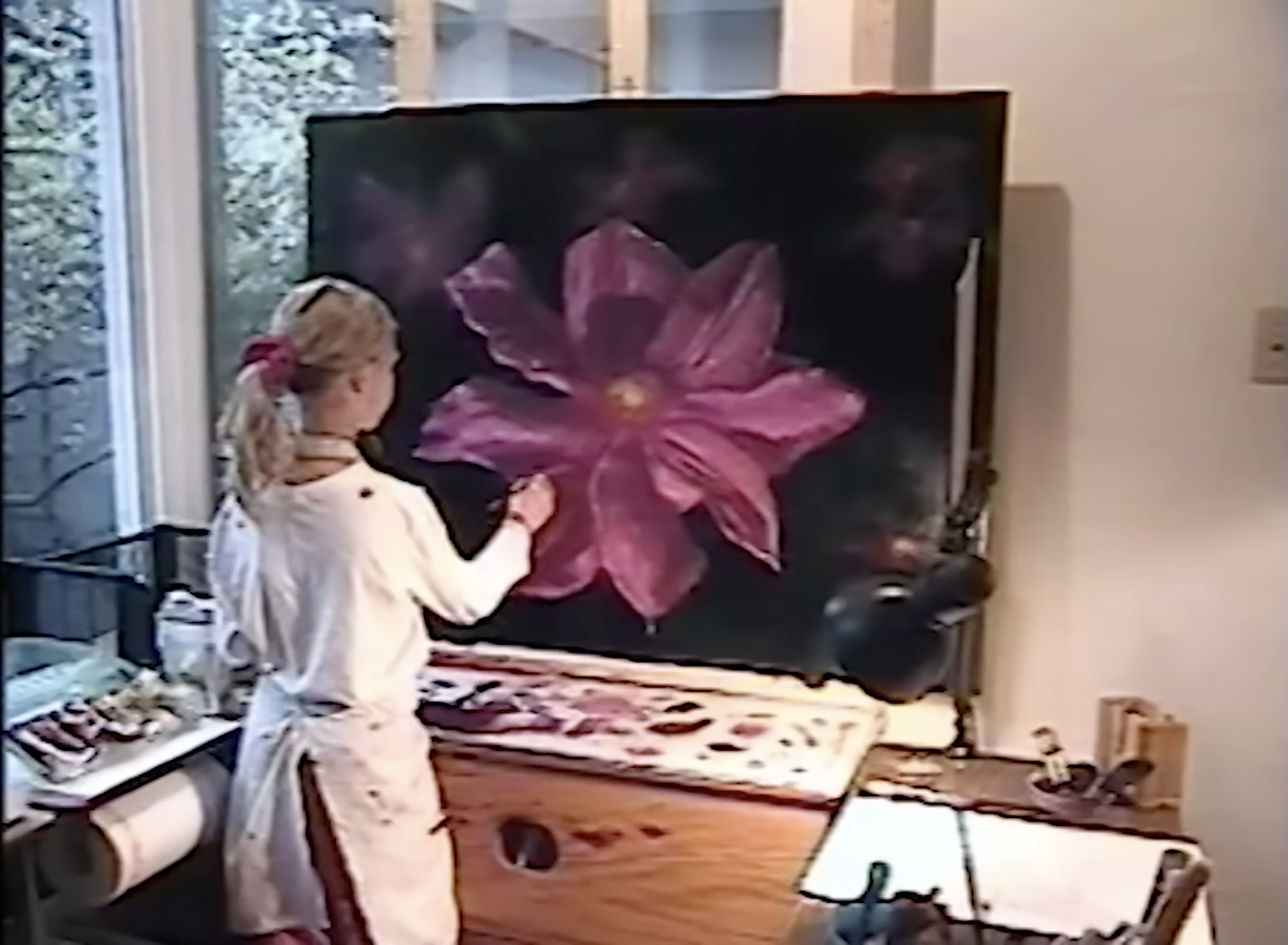 Akiane finishing a large pink flower painting at her easel