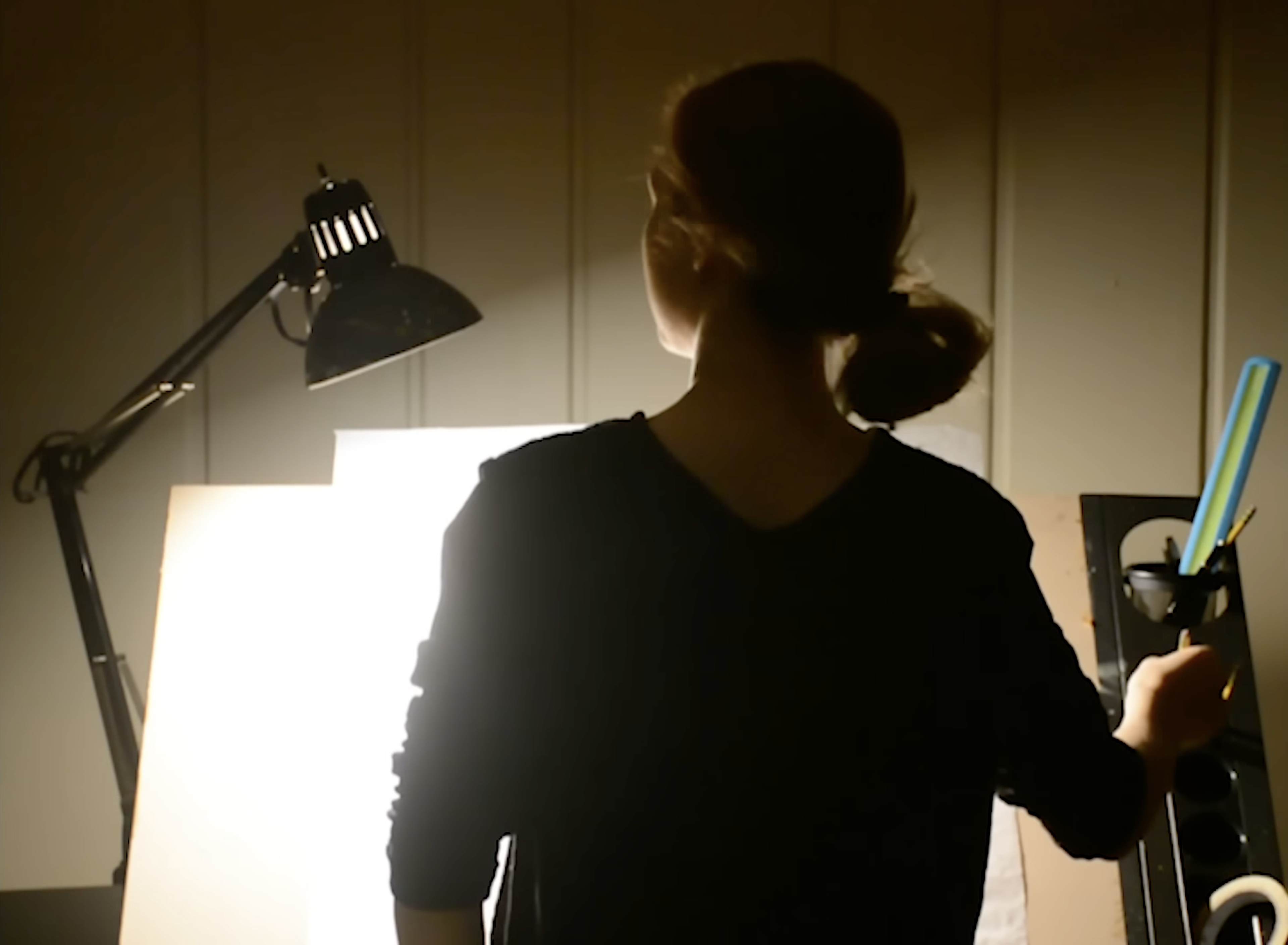 Akiane in silhouette before a glowing blank canvas