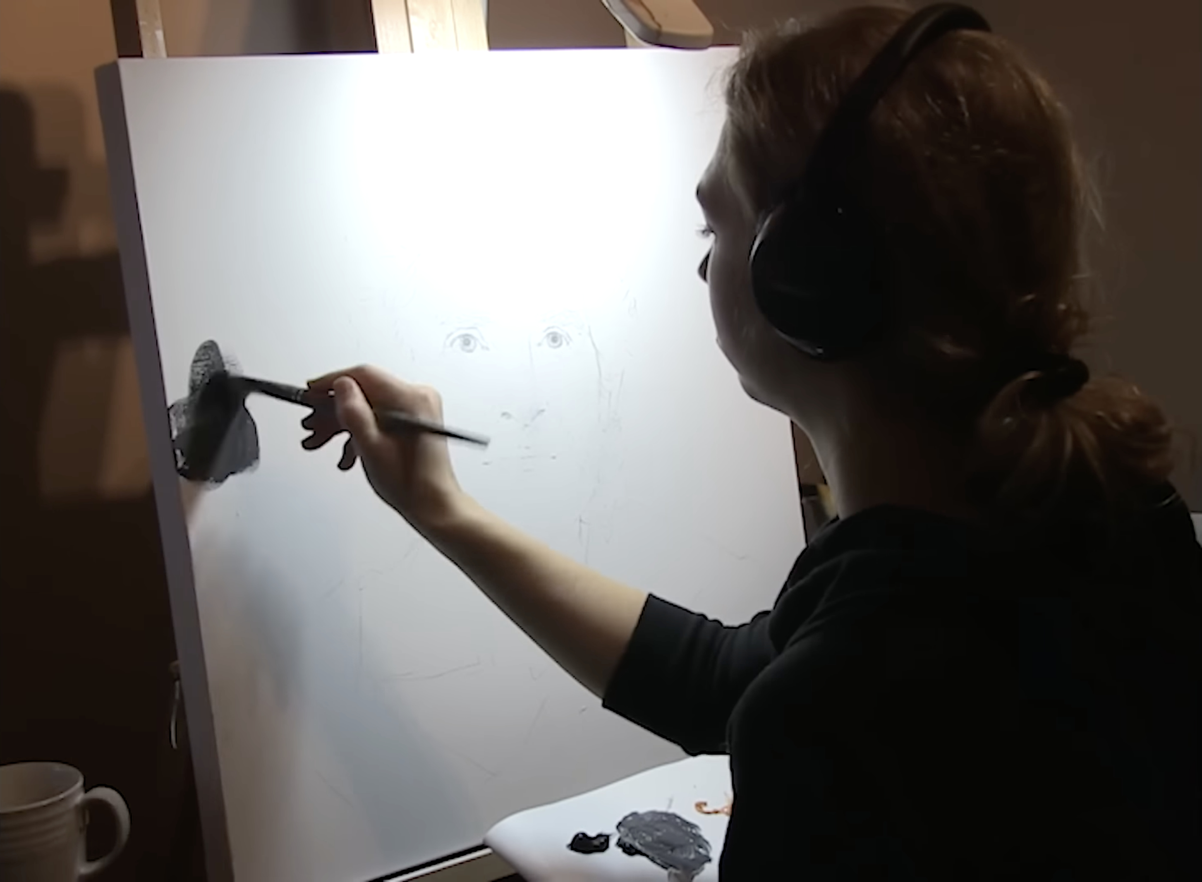 Akiane laying in the first dark strokes on a white canvas with penciled eyes