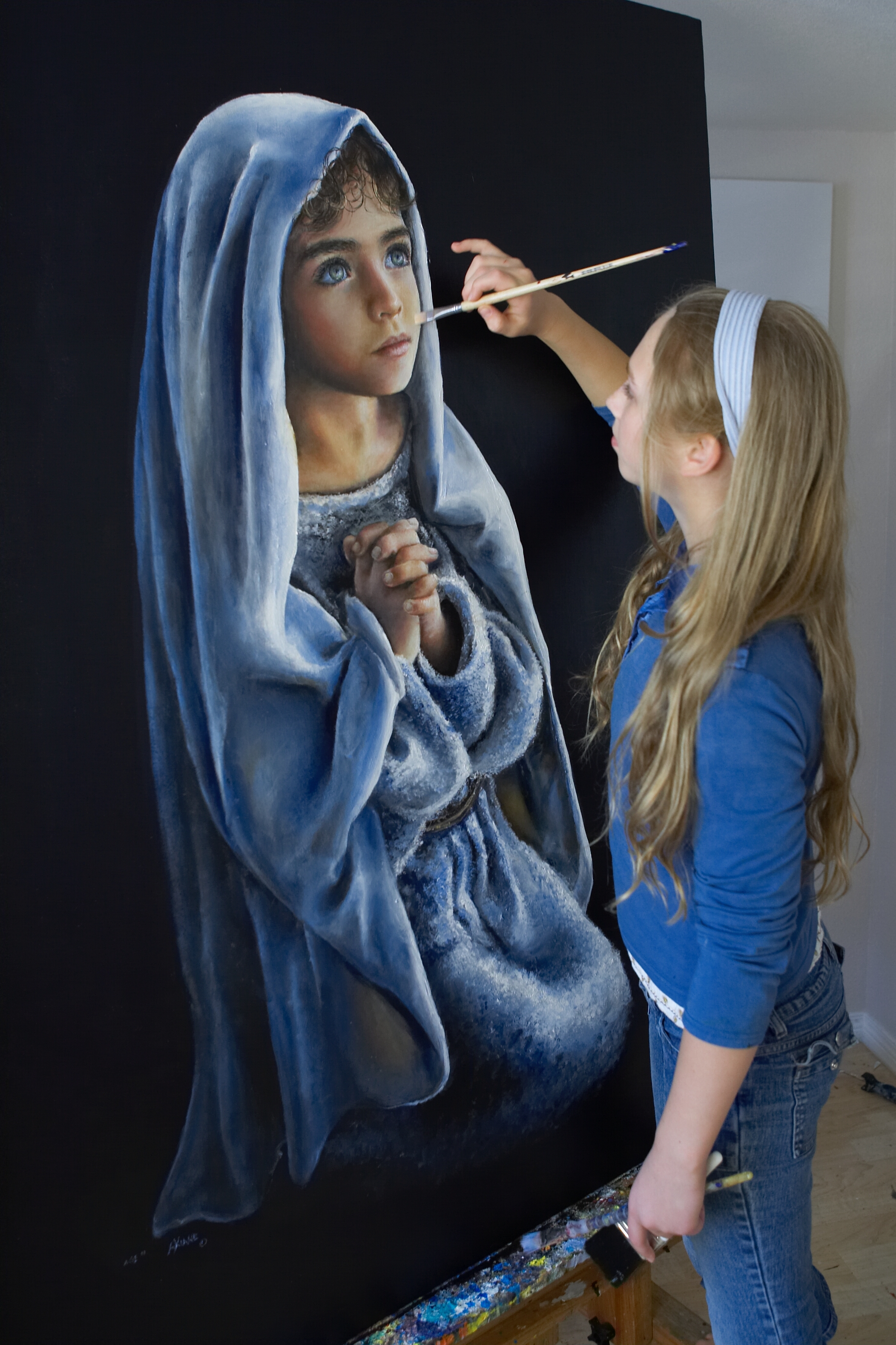 Akiane painting On My Knees, a child in a blue robe at prayer